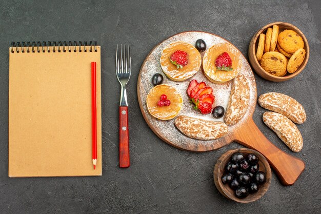 Vue de dessus de délicieuses crêpes aux fruits et gâteaux sucrés sur le dessert de gâteau de surface sombre