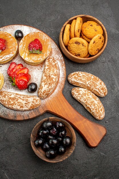 Vue de dessus de délicieuses crêpes aux fruits et gâteaux sucrés sur la surface sombre des gâteaux dessert sucré