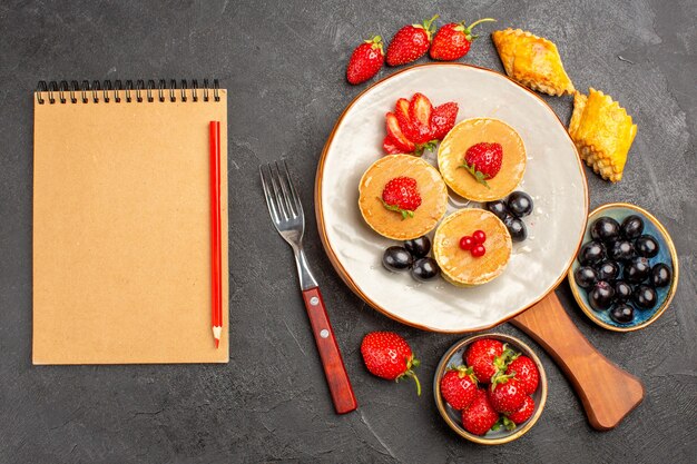 Vue de dessus de délicieuses crêpes aux fruits sur la surface sombre gâteau aux fruits tarte douce