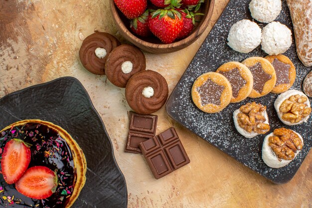 Vue de dessus de délicieuses crêpes avec des bonbons et des biscuits sur un bureau en bois