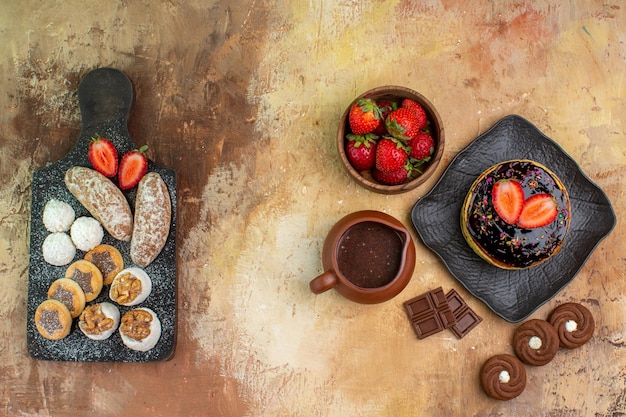 Vue de dessus de délicieuses crêpes avec des bonbons et des fruits sur un bureau en bois