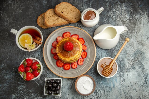 Vue de dessus de délicieuses crêpes avec du thé et des fruits à la lumière