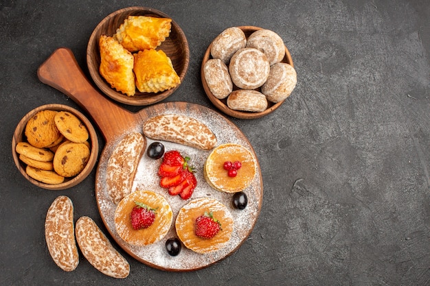 Vue de dessus de délicieuses crêpes avec des fruits et des gâteaux sucrés dans l'obscurité