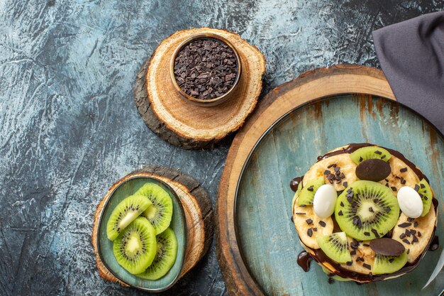 Vue de dessus de délicieuses crêpes avec des fruits tranchés et du chocolat sur une surface gris foncé, un petit-déjeuner de couleur douce, un dessert aux fruits au sucre