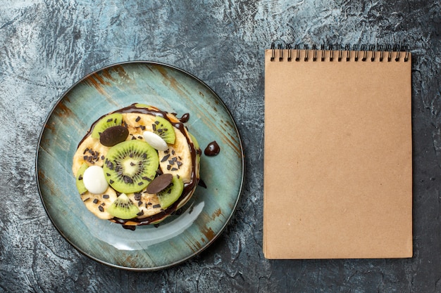 Vue de dessus de délicieuses crêpes avec des fruits tranchés et du chocolat sur une surface sombre, petit-déjeuner, sucre, fruits, gâteau sucré, dessert