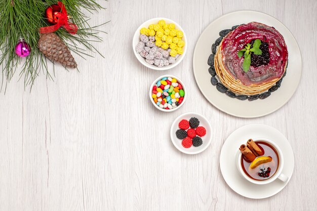 Vue de dessus de délicieuses crêpes à la gelée avec des bonbons et des raisins secs sur blanc