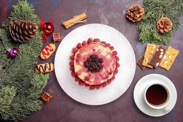 Vue de dessus de délicieuses crêpes à la gelée avec des fraises et une tasse de thé dans l'obscurité