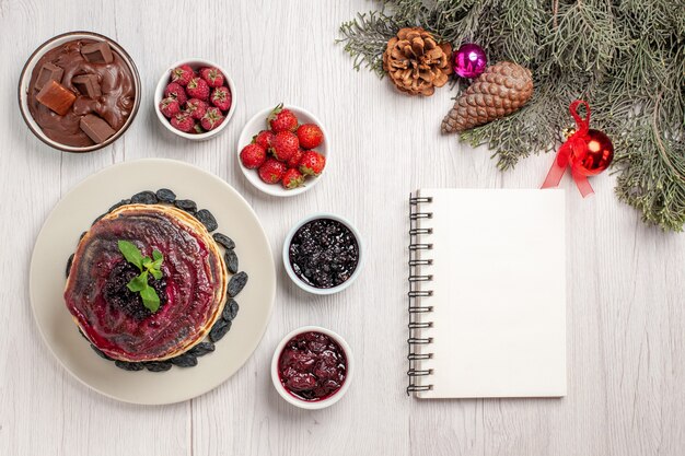 Vue de dessus de délicieuses crêpes à la gelée avec des fruits et des gelées sur blanc