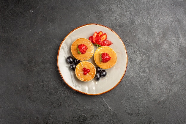 Vue de dessus de délicieuses crêpes peu formées avec des fruits dans le noir