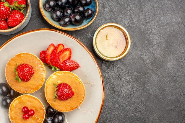 Photo gratuite vue de dessus de délicieuses crêpes peu formées avec des fruits sur le gris