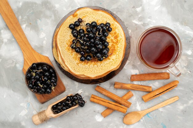 Une vue de dessus de délicieuses crêpes rondes délicieuses et rondes formées de bleuets et de pâte à crêpes à la cannelle