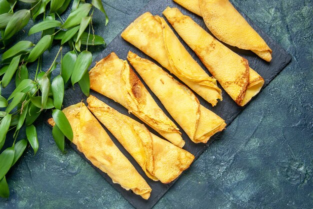 Vue de dessus de délicieuses crêpes roulées bordées sur fond sombre couleur repas tarte pâte à viande gâteau pâtisserie sucrée