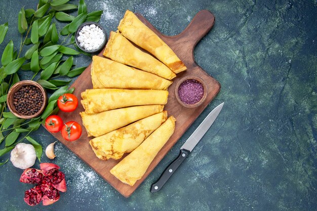 Vue de dessus de délicieuses crêpes roulées sur fond bleu foncé pâtisserie pâte à gâteau tarte couleur viande repas de gâteau sucré