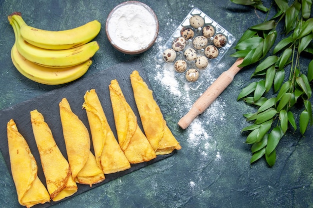 Photo gratuite vue de dessus de délicieuses crêpes avec de savoureuses bananes sur fond sombre pâte à gâteau repas chaud tarte sucrée viande couleur pâtisserie