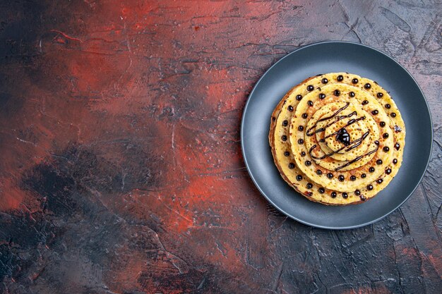 Vue de dessus de délicieuses crêpes sucrées avec du glaçage sur un bureau sombre