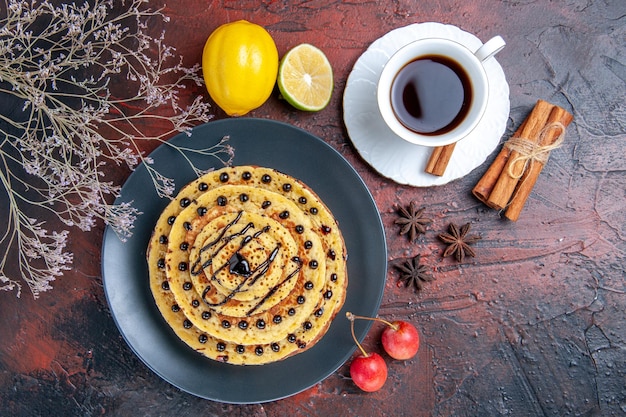 Photo gratuite vue de dessus de délicieuses crêpes sucrées avec du thé sur la surface sombre