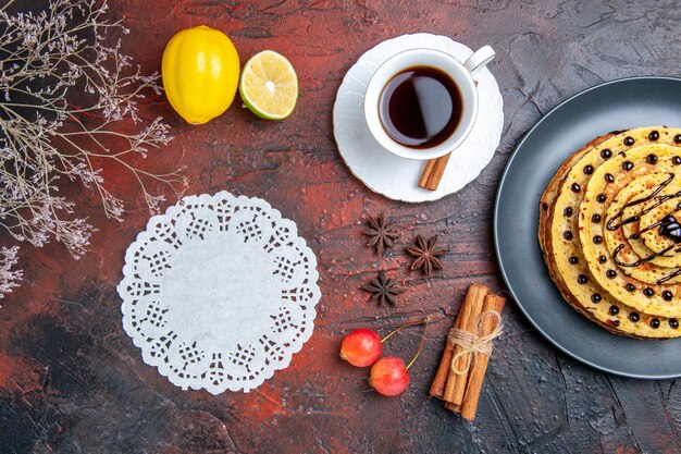 Vue de dessus de délicieuses crêpes sucrées avec du thé sur la surface sombre