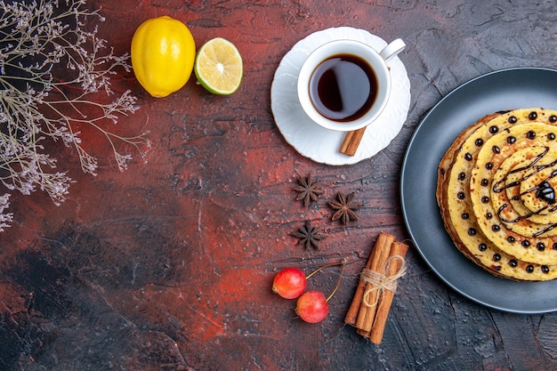 Vue de dessus de délicieuses crêpes sucrées avec du thé sur la surface sombre