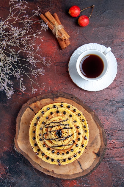 Vue de dessus de délicieuses crêpes sucrées avec une tasse de thé sur une surface sombre