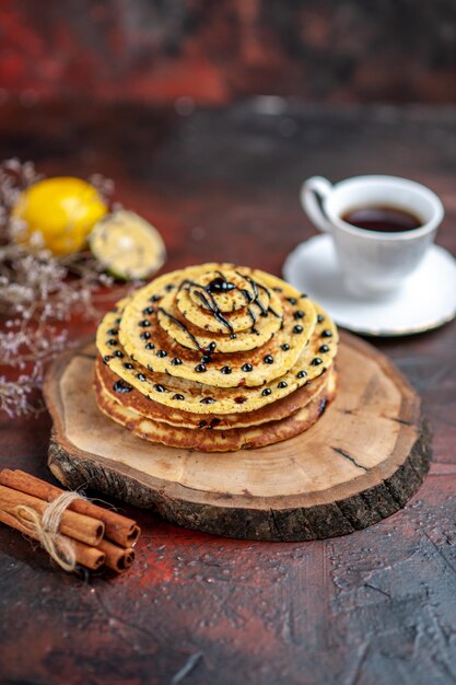 Vue de dessus de délicieuses crêpes sucrées avec une tasse de thé sur une surface sombre