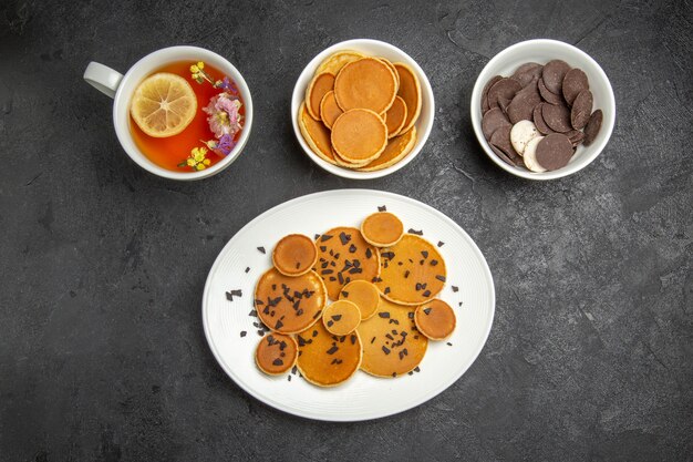 Vue de dessus de délicieuses crêpes avec une tasse de thé sur le fond sombre