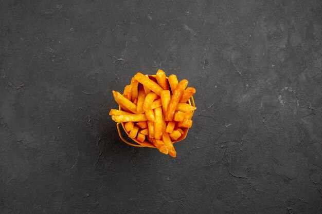 Vue de dessus de délicieuses frites à l'intérieur du paquet sur le repas de burger de plat de pommes de terre de restauration rapide sur fond sombre