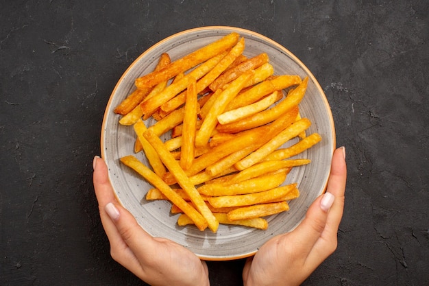 Vue de dessus de délicieuses frites à l'intérieur de la plaque sur le fond sombre plat de sandwich repas de pommes de terre burger fast-food