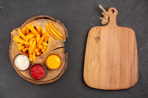 Vue de dessus de délicieuses frites avec sauces sur gris