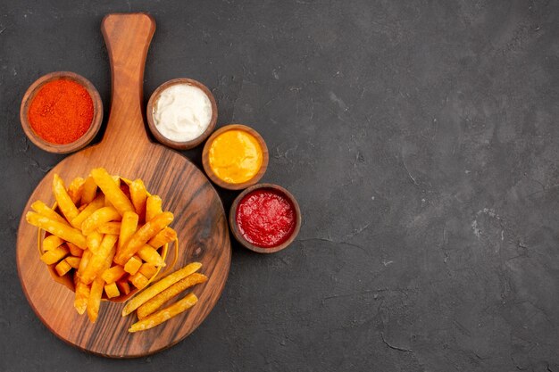 Vue de dessus de délicieuses frites avec sauces sur tableau noir