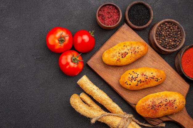 Vue de dessus de délicieuses galettes cuites au four avec différents assaisonnements sur une pâtisserie de bureau foncé