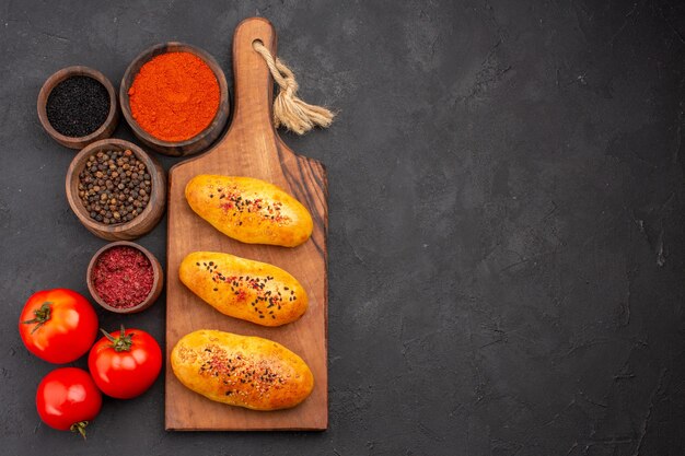 Vue de dessus de délicieuses galettes cuites au four fraîchement sorties du four avec des assaisonnements sur le fond gris tarte four pâte pâtisserie viande gâteau cuire