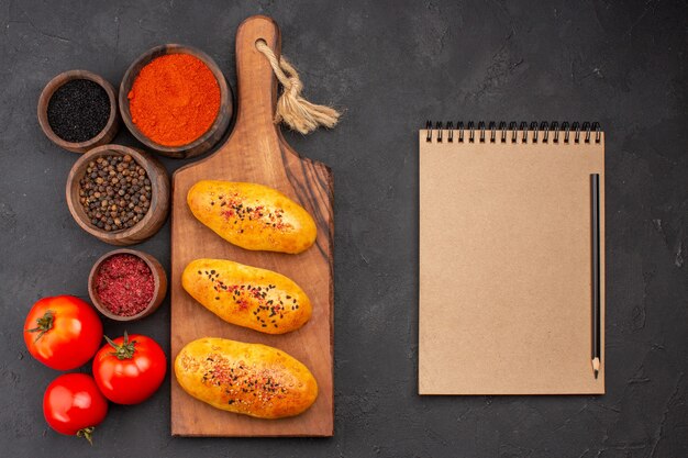 Vue de dessus de délicieuses galettes cuites au four fraîchement sorties du four avec des assaisonnements sur le fond gris tarte four pâte pâtisserie viande gâteau cuire