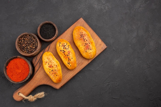 Vue de dessus de délicieuses galettes cuites au four fraîchement sorties du four avec assaisonnements sur fond gris tarte four pâtisserie gâteau à la viande