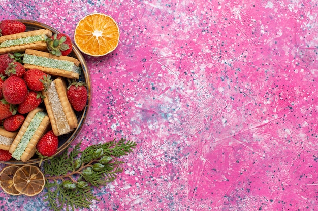 Vue de dessus de délicieuses gaufres avec des fraises rouges fraîches sur une surface rose