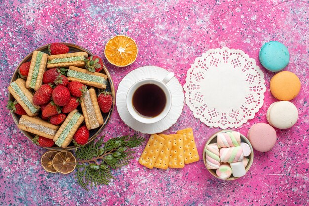 Photo gratuite vue de dessus de délicieuses gaufres avec tasse de thé et fraises rouges fraîches sur la surface rose