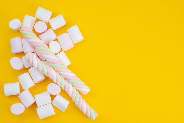 Une vue de dessus de délicieuses guimauves sur des bonbons de couleur sucrée jaune, sucre