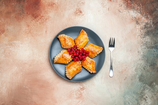 Vue de dessus de délicieuses pâtisseries sucrées aux fruits rouges sur une pâtisserie à tarte blanche sucrée