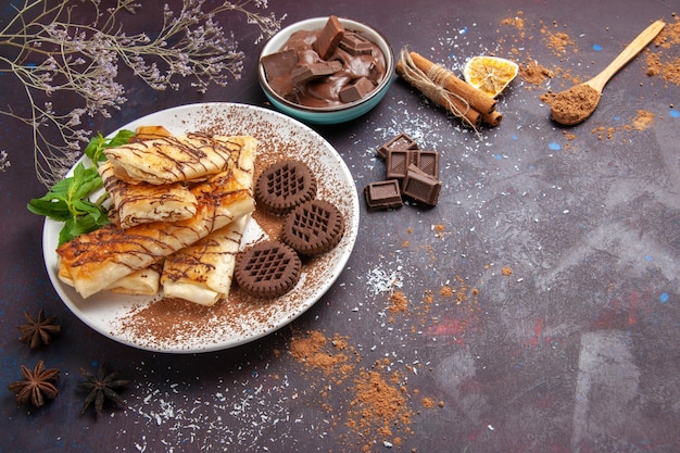 Vue de dessus de délicieuses pâtisseries sucrées avec des biscuits au chocolat sur l'espace sombre