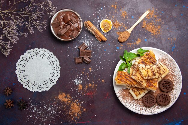 Vue de dessus de délicieuses pâtisseries sucrées avec des biscuits au chocolat sur un sol sombre gâteau au thé biscuit au sucre dessert sucré