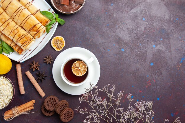 Vue de dessus de délicieuses pâtisseries sucrées avec des biscuits et du thé sur l'espace sombre