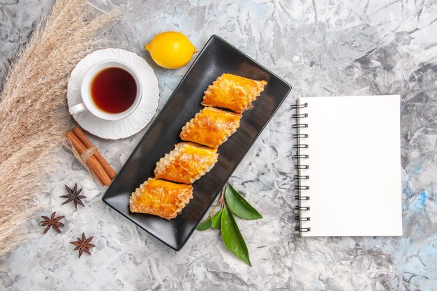 Vue de dessus de délicieuses pâtisseries sucrées avec du thé sur un gâteau à la tarte sucrée blanc clair