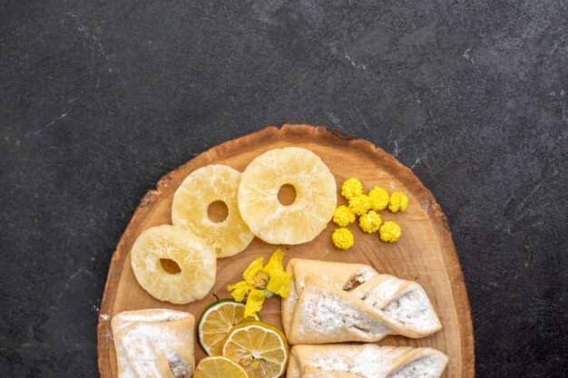 Vue de dessus de délicieuses pâtisseries avec des tranches de fruits secs sur l'espace gris