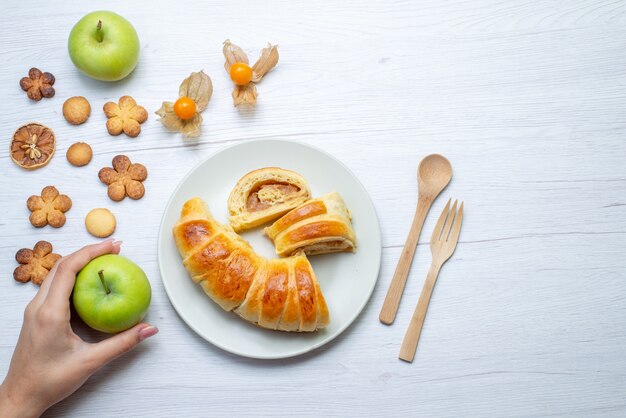 Vue de dessus de délicieuses pâtisseries en tranches à l'intérieur de la plaque avec remplissage avec pommes et biscuits sur un bureau blanc, biscuit pâtisserie biscuit sucre sucré