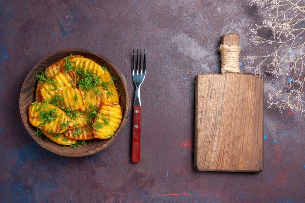 Vue de dessus de délicieuses pommes de terre cuites avec des légumes verts à l'intérieur d'une assiette brune sur une surface sombre plat de repas cuisson cips dîner pomme de terre