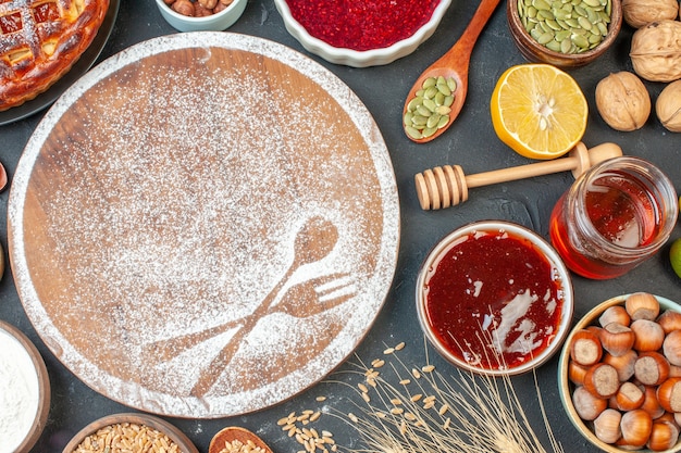 Vue de dessus de délicieuses tartes aux fruits avec du miel de noix et de la confiture sur une table sombre