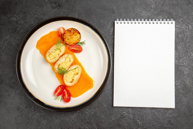 Vue de dessus de délicieuses tartes aux pommes de terre avec de la citrouille à l'intérieur de la plaque sur une tranche de dîner de plat de couleur de cuisson au four de bureau gris