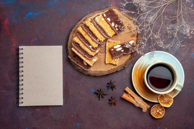 Vue de dessus de délicieuses tranches de gâteau aux noix et tasse de thé sur fond noir