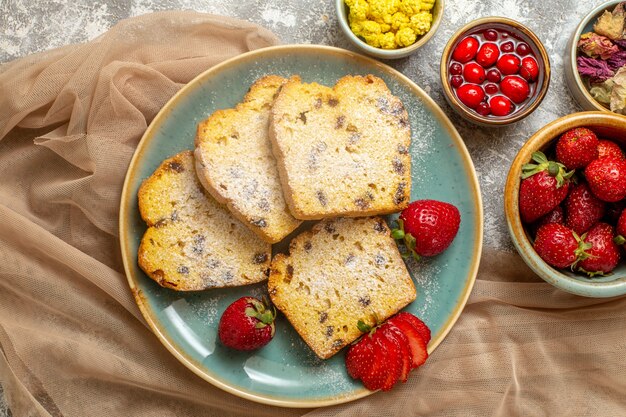 Vue de dessus de délicieuses tranches de gâteau avec des fraises fraîches sur un sol clair