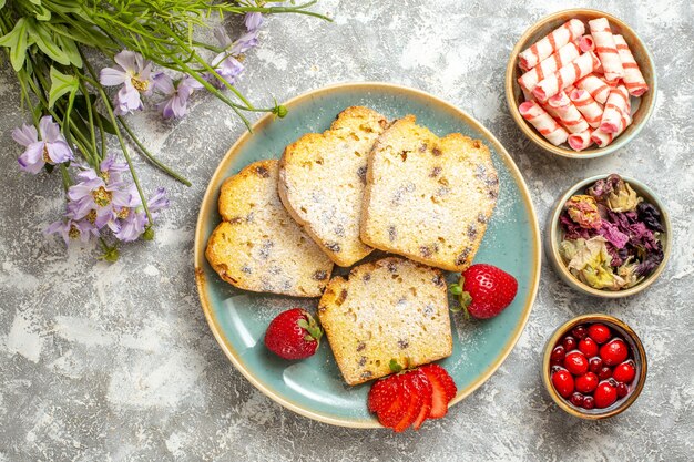 Vue de dessus de délicieuses tranches de gâteau avec des fraises à la lumière