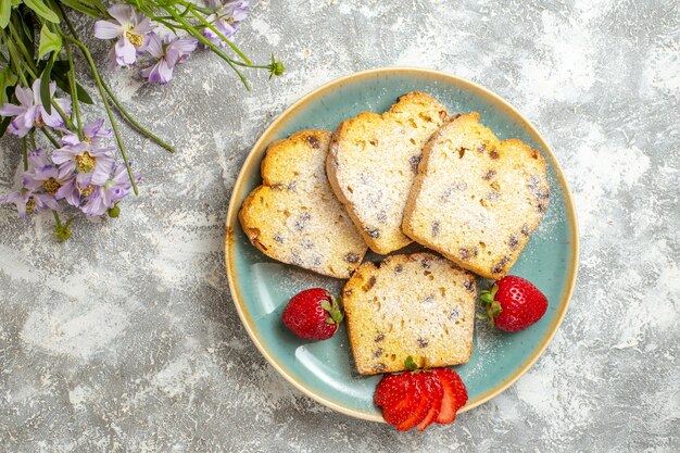 Vue de dessus de délicieuses tranches de gâteau avec des fraises à la lumière